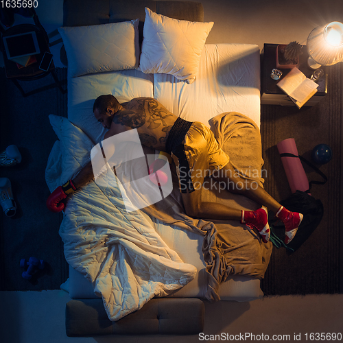 Image of Top view of young professional boxer, fighter sleeping at his bedroom in sportwear with gloves