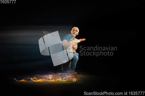 Image of Fast delivery service - deliveryman on chair driving with order in fire on dark background