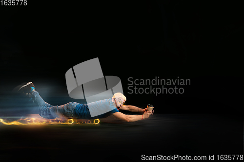 Image of Fast delivery service - deliveryman on skateboard driving with order in fire on dark background