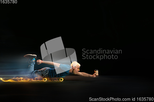 Image of Fast delivery service - deliveryman on skateboard driving with order in fire on dark background