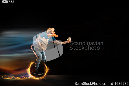 Image of Fast delivery service - deliveryman on unicycle driving with order in fire on dark background