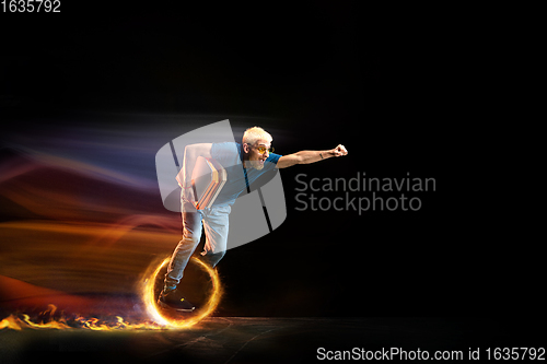 Image of Fast delivery service - deliveryman on unicycle driving with order in fire on dark background