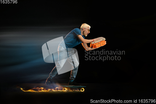 Image of Fast delivery service - deliveryman on unicycle driving with order in fire on dark background