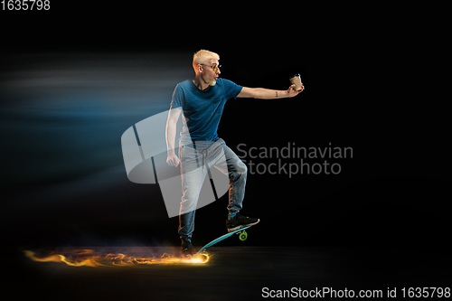 Image of Fast delivery service - deliveryman on skateboard driving with order in fire on dark background