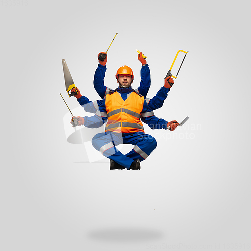 Image of Handsome contractor, multi-armed builder levitating isolated on grey studio background