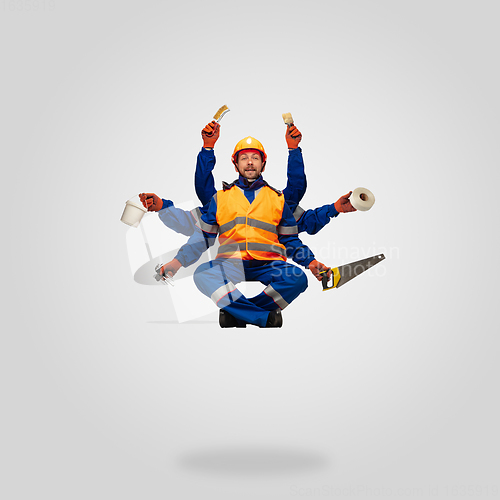 Image of Handsome contractor, multi-armed builder levitating isolated on grey studio background