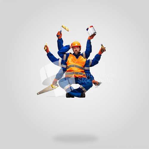 Image of Handsome contractor, multi-armed builder levitating isolated on grey studio background