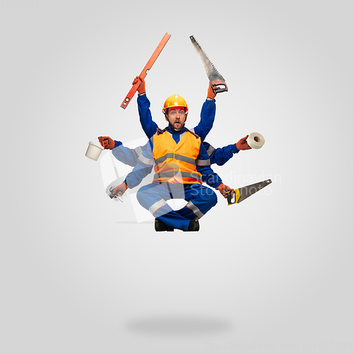 Image of Handsome contractor, multi-armed builder levitating isolated on grey studio background