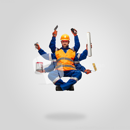 Image of Handsome contractor, multi-armed builder levitating isolated on grey studio background