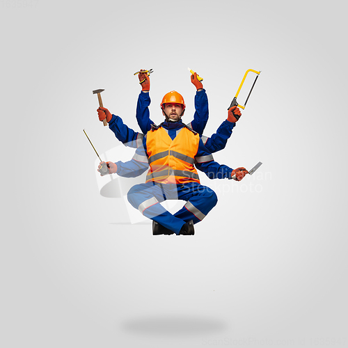 Image of Handsome contractor, multi-armed builder levitating isolated on grey studio background