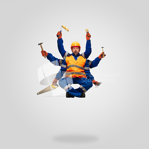 Image of Handsome contractor, multi-armed builder levitating isolated on grey studio background