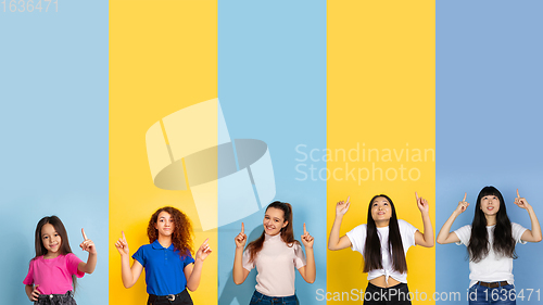 Image of Young people pointing up smiling on multicolored background. Human emotions, facial expression concept. Trendy colors. Creative collage.