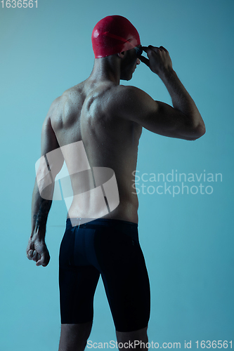 Image of Professional male swimmer with hat and goggles in motion and action, healthy lifestyle and movement concept. Neoned style.