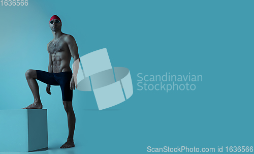 Image of Professional male swimmer with hat and goggles in motion and action, healthy lifestyle and movement concept. Neoned style.