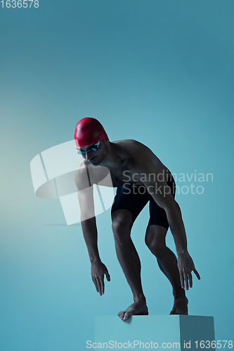 Image of Professional male swimmer with hat and goggles in motion and action, healthy lifestyle and movement concept. Neoned style.