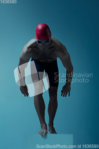 Image of Professional male swimmer with hat and goggles in motion and action, healthy lifestyle and movement concept. Neoned style.