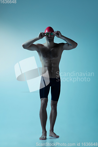 Image of Professional male swimmer with hat and goggles in motion and action, healthy lifestyle and movement concept. Neoned style.