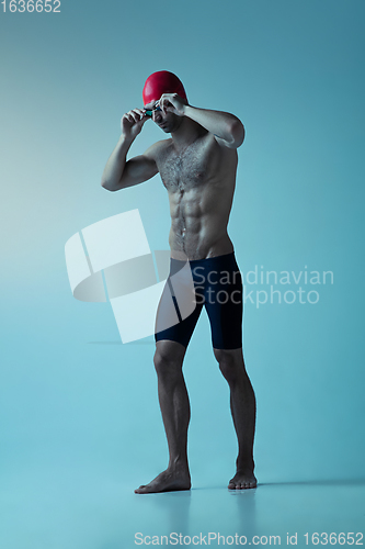 Image of Professional male swimmer with hat and goggles in motion and action, healthy lifestyle and movement concept. Neoned style.