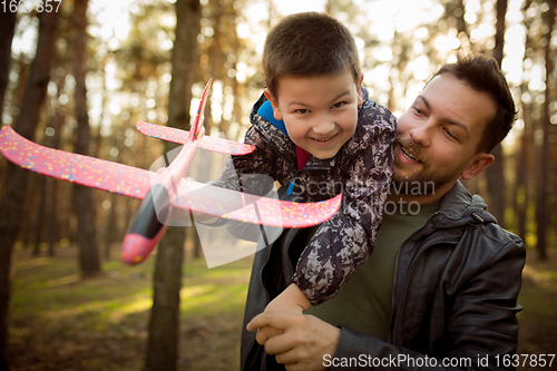 Image of Father and son walking and having fun in autumn forest, look happy and sincere