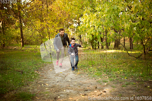 Image of Father and son walking and having fun in autumn forest, look happy and sincere