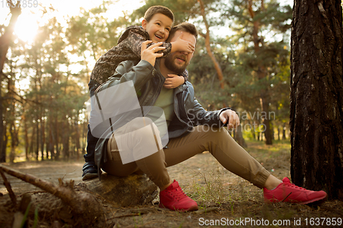 Image of Father and son walking and having fun in autumn forest, look happy and sincere