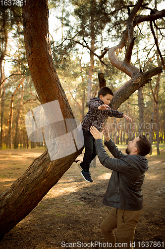 Image of Father and son walking and having fun in autumn forest, look happy and sincere