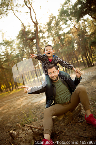 Image of Father and son walking and having fun in autumn forest, look happy and sincere