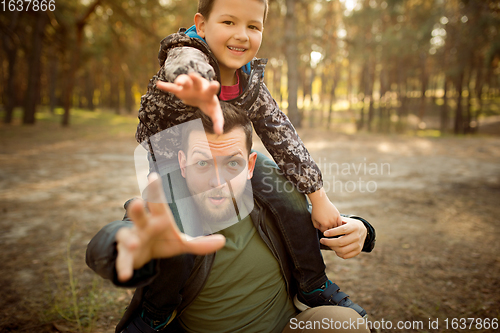 Image of Father and son walking and having fun in autumn forest, look happy and sincere