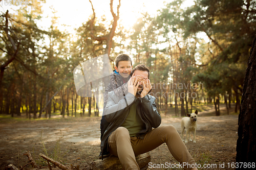 Image of Father and son walking and having fun in autumn forest, look happy and sincere