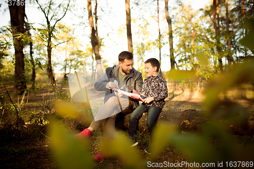 Image of Father and son walking and having fun in autumn forest, look happy and sincere