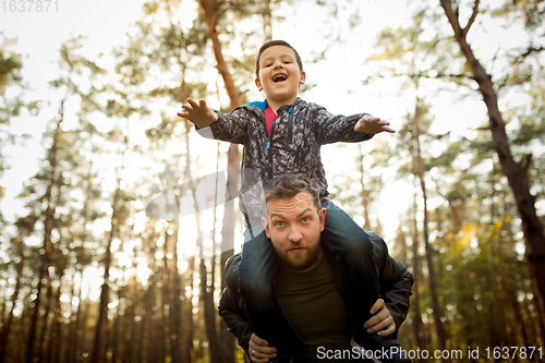 Image of Father and son walking and having fun in autumn forest, look happy and sincere