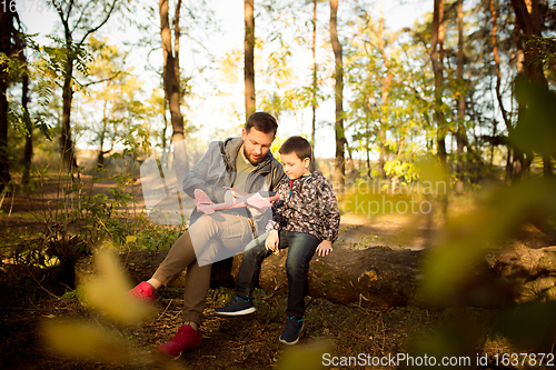 Image of Father and son walking and having fun in autumn forest, look happy and sincere