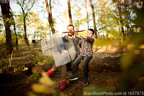 Image of Father and son walking and having fun in autumn forest, look happy and sincere