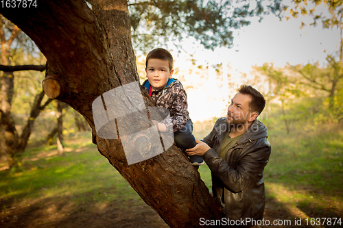 Image of Father and son walking and having fun in autumn forest, look happy and sincere