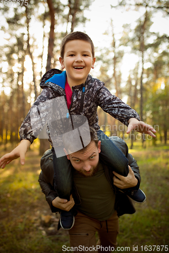 Image of Father and son walking and having fun in autumn forest, look happy and sincere