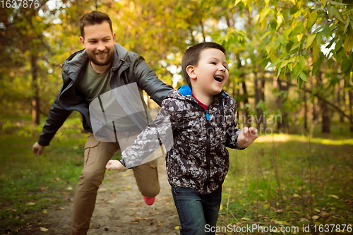 Image of Father and son walking and having fun in autumn forest, look happy and sincere