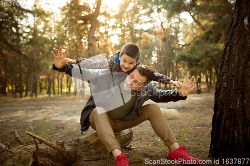 Image of Father and son walking and having fun in autumn forest, look happy and sincere