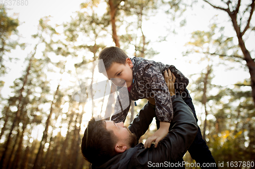 Image of Father and son walking and having fun in autumn forest, look happy and sincere