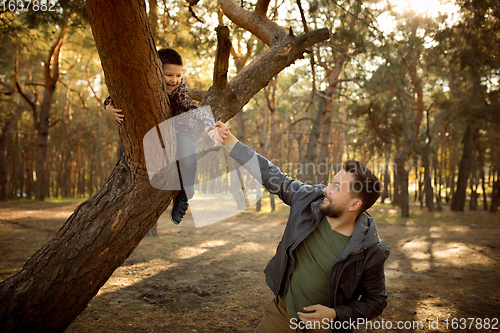 Image of Father and son walking and having fun in autumn forest, look happy and sincere