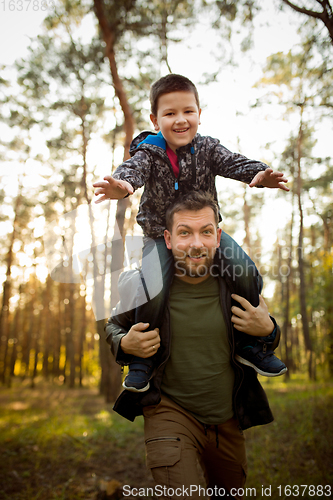 Image of Father and son walking and having fun in autumn forest, look happy and sincere