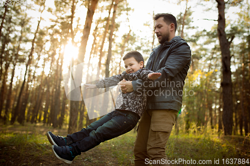 Image of Father and son walking and having fun in autumn forest, look happy and sincere