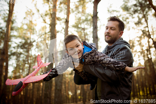 Image of Father and son walking and having fun in autumn forest, look happy and sincere