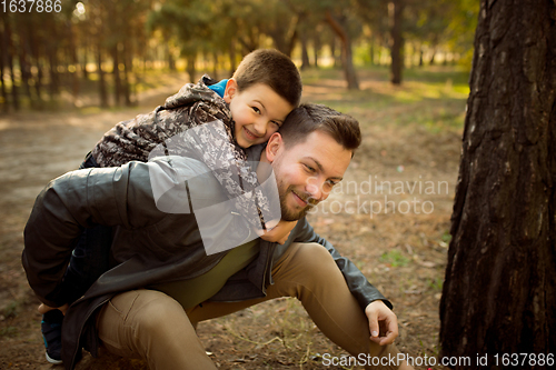 Image of Father and son walking and having fun in autumn forest, look happy and sincere