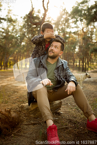 Image of Father and son walking and having fun in autumn forest, look happy and sincere