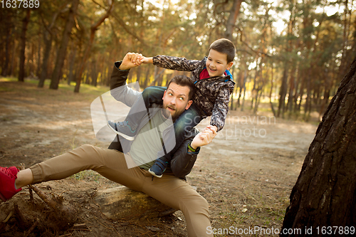 Image of Father and son walking and having fun in autumn forest, look happy and sincere