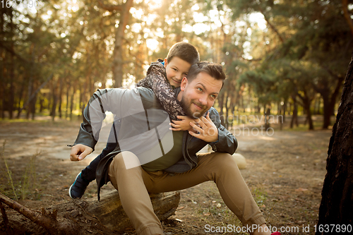 Image of Father and son walking and having fun in autumn forest, look happy and sincere