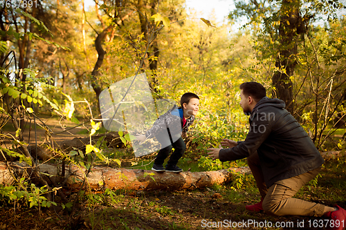 Image of Father and son walking and having fun in autumn forest, look happy and sincere