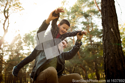 Image of Father and son walking and having fun in autumn forest, look happy and sincere