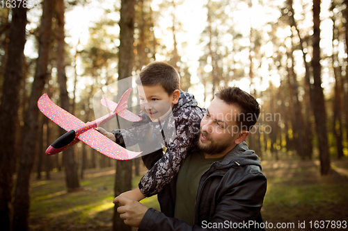 Image of Father and son walking and having fun in autumn forest, look happy and sincere