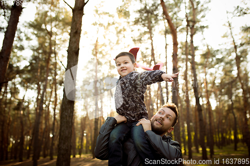 Image of Father and son walking and having fun in autumn forest, look happy and sincere